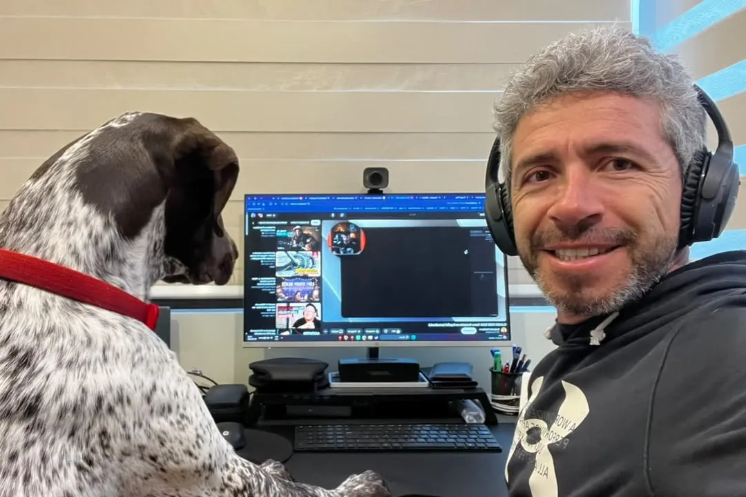 Jorge, con audífonos, sonríe a la cámara mientras Fili mira la pantalla de su computador